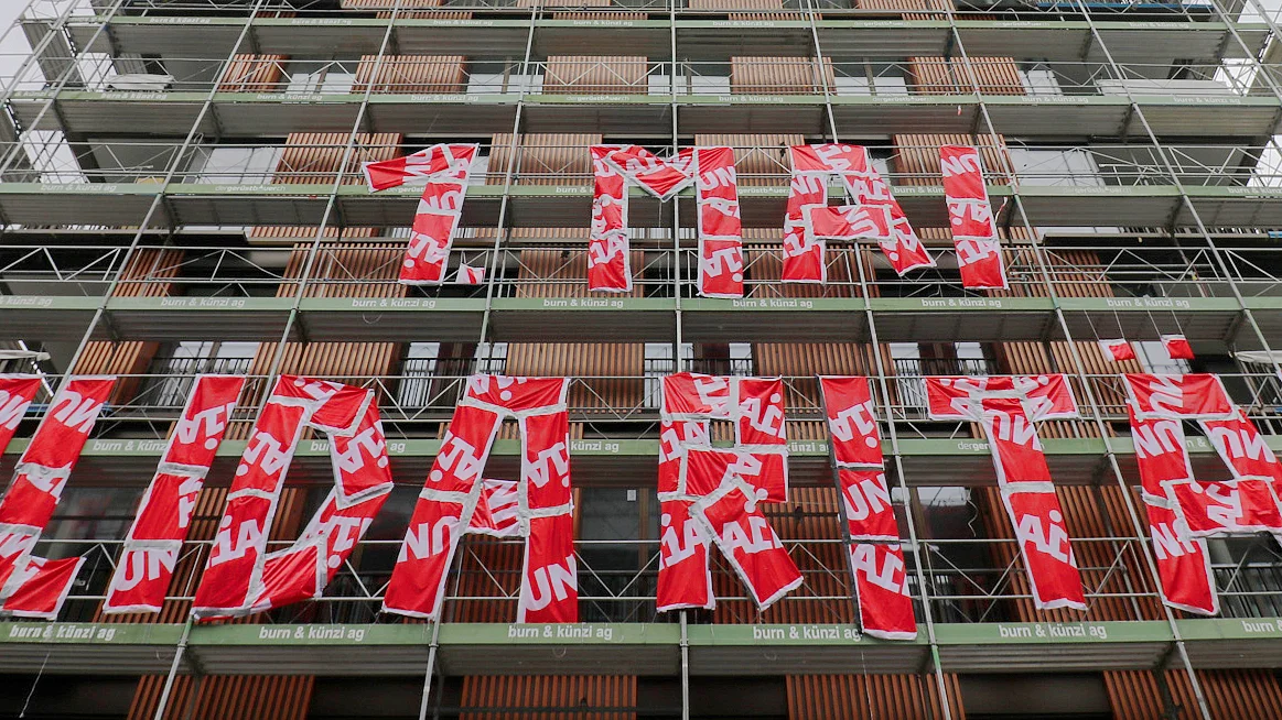 An einem Baugerüst ist der Text: «1. Mai - Solidarität» aus roten Unia-Fahnen angebracht.
