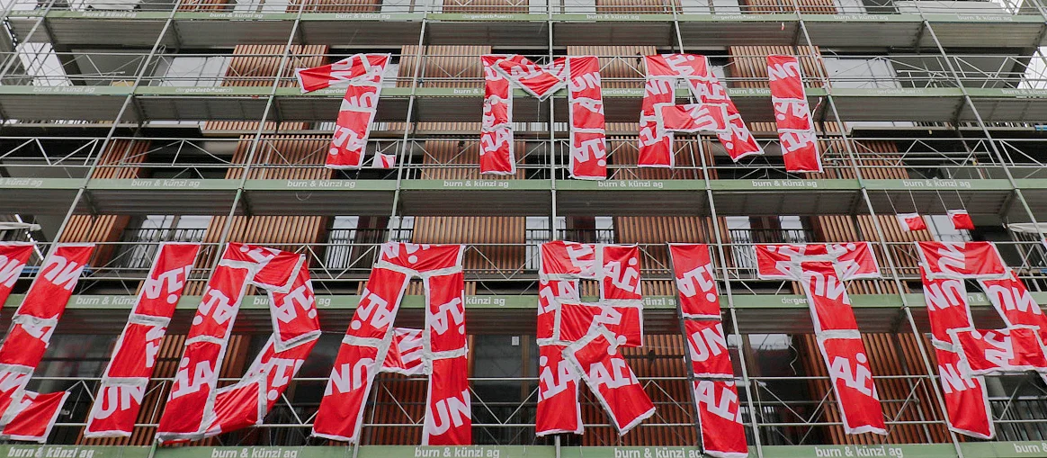 An einem Baugerüst ist der Text: «1. Mai - Solidarität» aus roten Unia-Fahnen angebracht.
