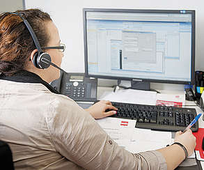 Gewerkschaftssekretärin mit Headset vor Computer